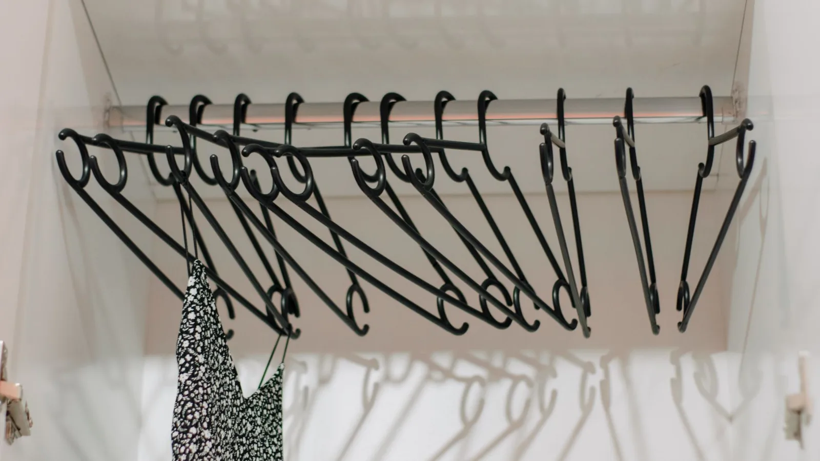 Minimalist closet interior with black hangers and a single patterned dress.