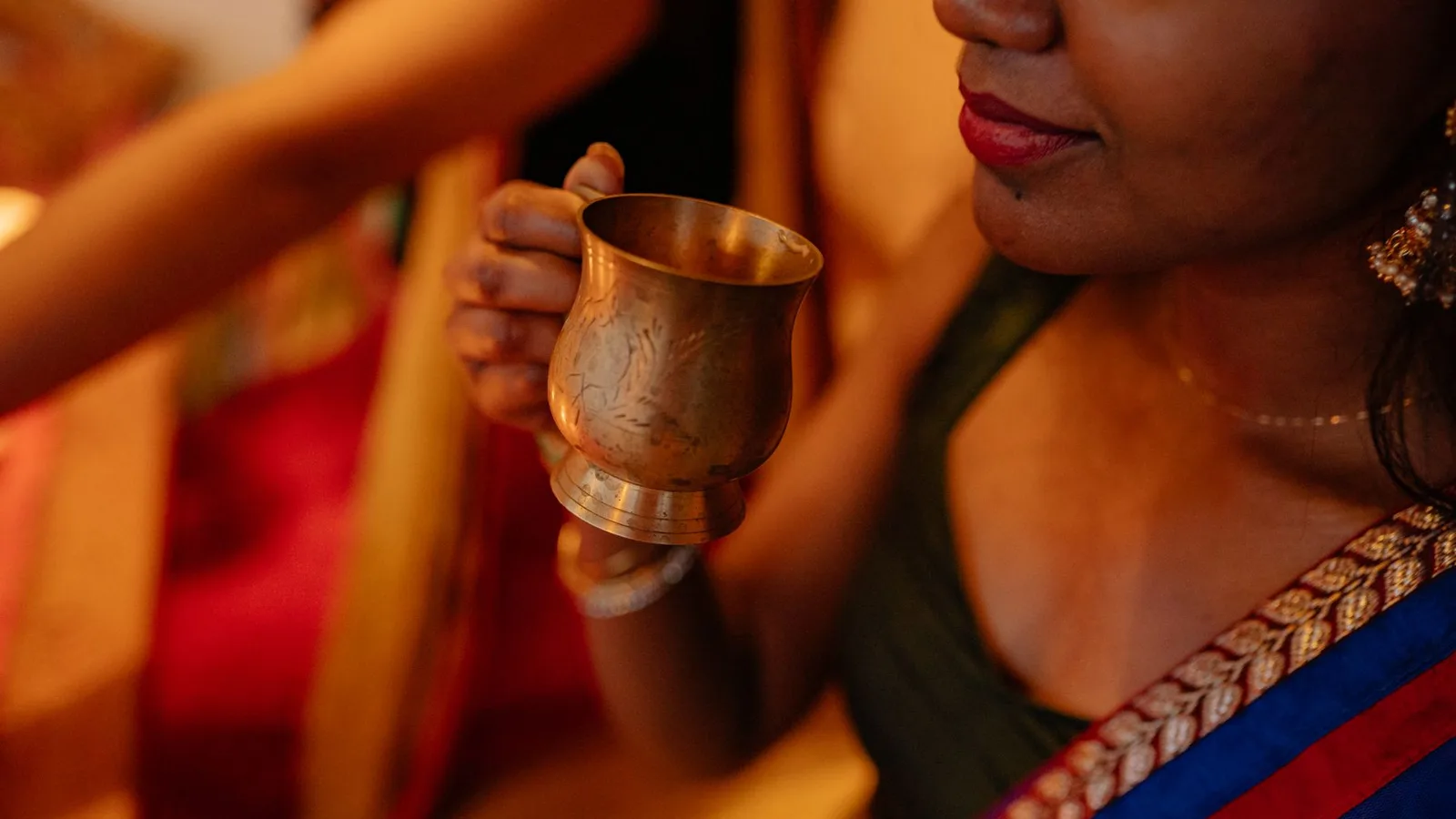 Close-up of a woman holding a traditional cup, celebrating a festive occasion.